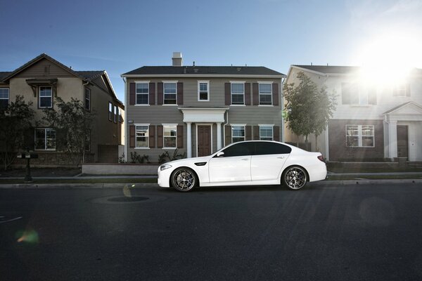 White BMW in profile against the background of houses