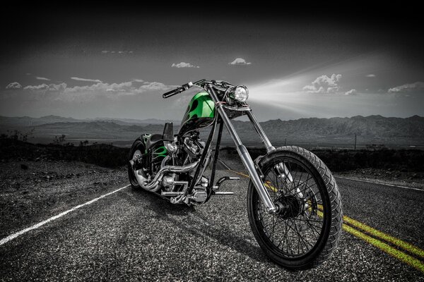 Black and white landscape with a green motorcycle on the highway