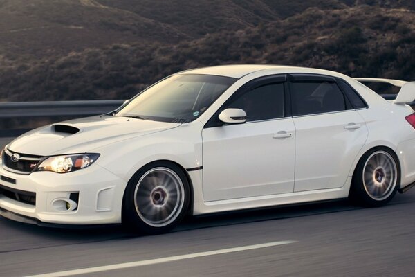 White Subaru sedan on a mountain highway