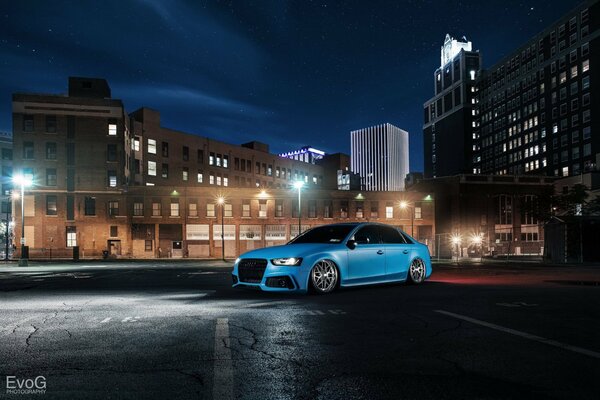 A blue car stands against the background of buildings