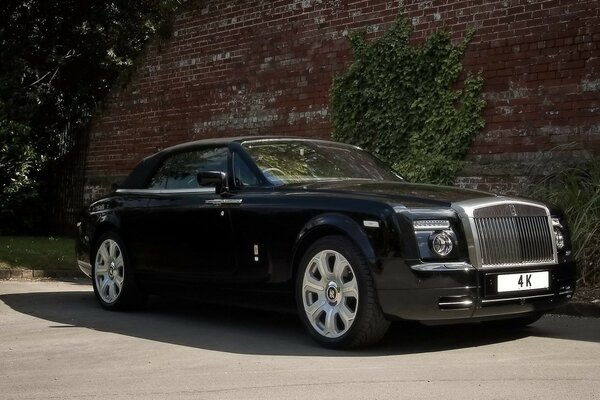 Black rolls-royce on the background of an old burgundy wall