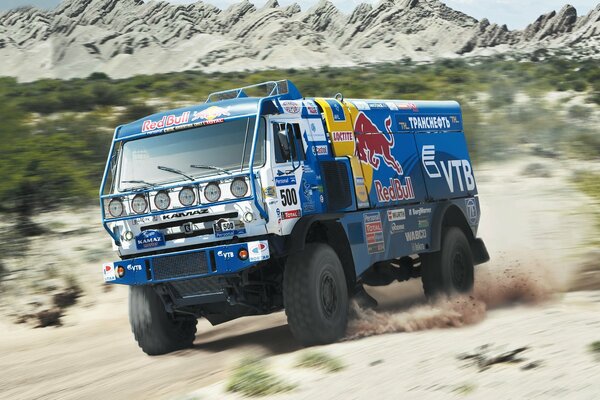 Kamaz Dakar rides on the sand against the backdrop of mountains