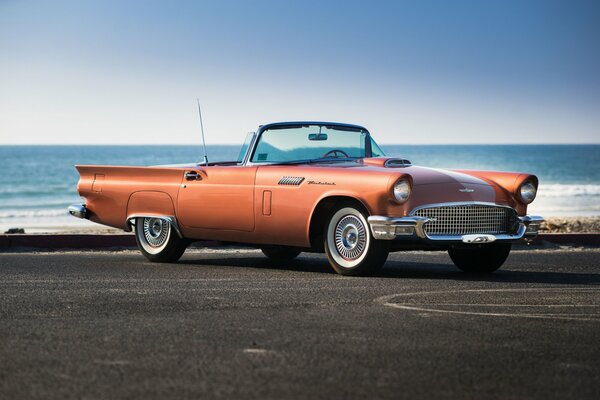 Viejo Ford-thunderbird frente al mar tranquilo