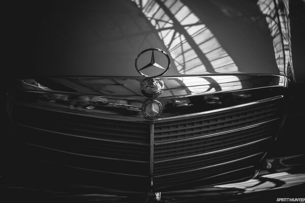 Imagen en blanco y negro del capó y la parrilla del motor mercedes con el emblema