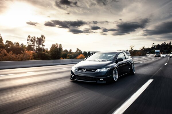 A black Honda car is driving on a high-speed highway