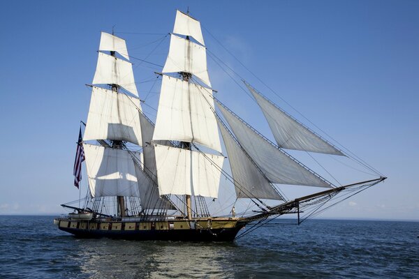 Un barco con velas blancas navega en el mar