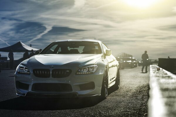 An image of a BMW car on a background of clouds and a man