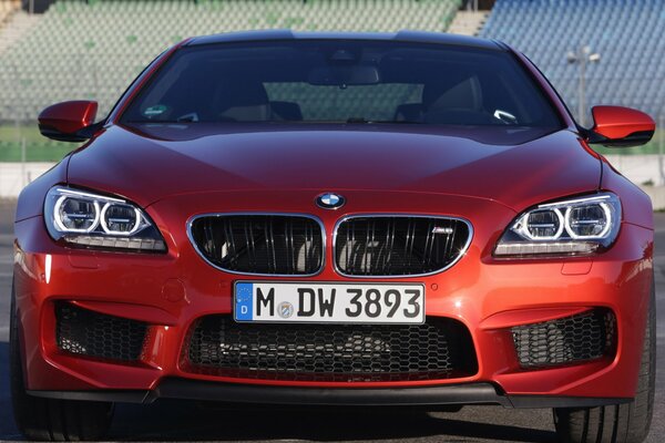 Red BMW car in front on the background of the stands