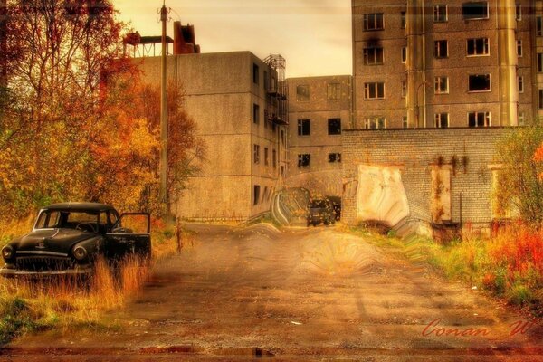 Coche abandonado en el fondo de la ciudad fantasma de otoño