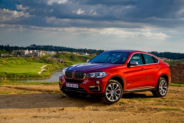 Czerwony samochód BMW na tle łąki