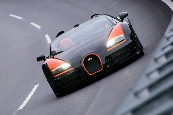 El coche de Bugatti Veyron en color negro y naranja en la pista