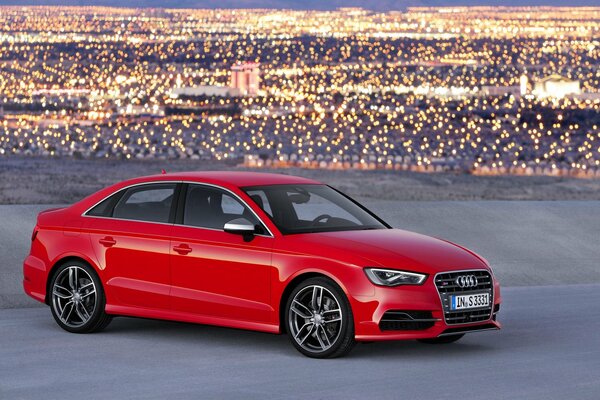 Against the background of city lights is a red audi a3 sedan