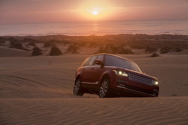 Jeep promenades à travers les sables au coucher du soleil