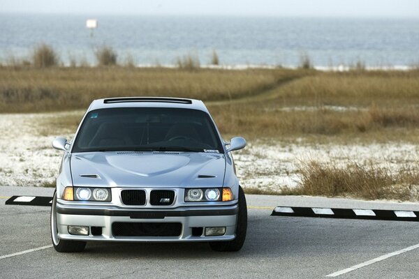 Silver bmw e36 car on the shore