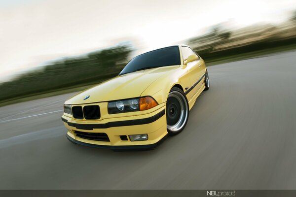 BMW E36 coupé amarillo en movimiento