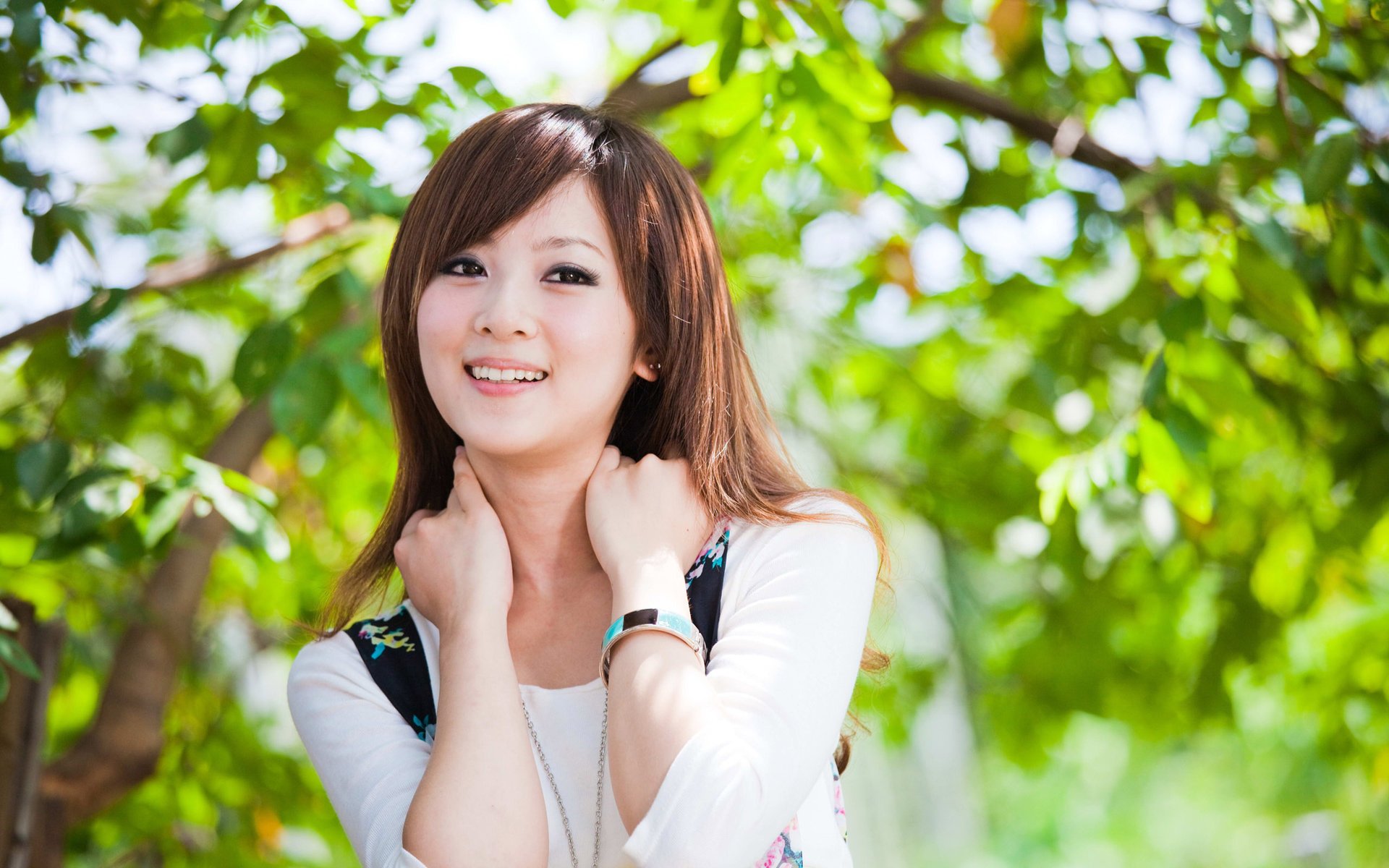 fille asiatique sourire arbres feuillage verdure feuilles cheveux cheveux bruns yeux regard