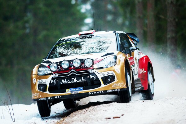 A sports car rushes along a snowy road in the middle of the forest