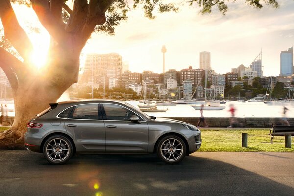 Srebrne Porsche Macan S zaparkowane na nabrzeżu na tle wieżowców