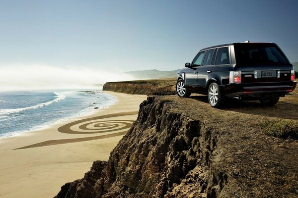 Schwarzes Auto in der Nähe einer Klippe am Meer