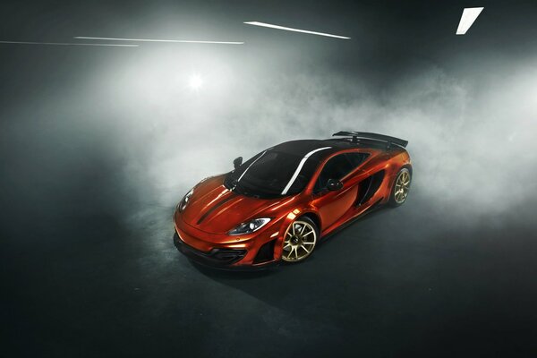 Orange McLaren MP4-12C stands in a cloud of smoke