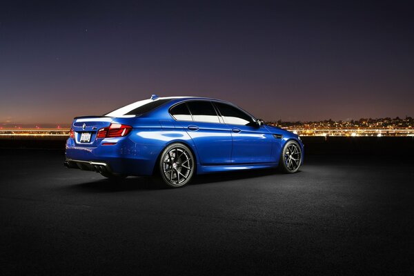 Coche azul bmw. Ciudad nocturna en el horizonte