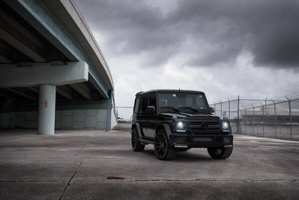 Czarny mercedes G63 na tle mostu i nieba