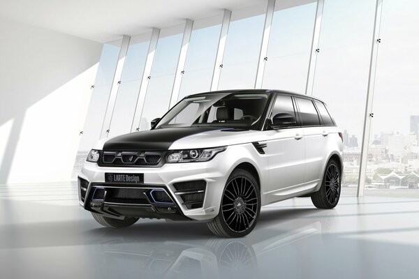 Серебристый Range Rover larte на фоне огромных окон автоколона