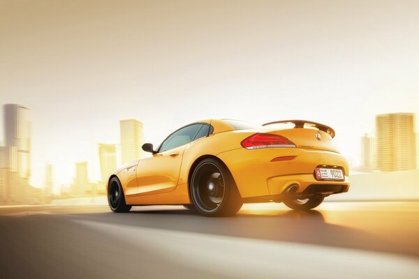 Yellow BMW z4 rushes at speed towards sunset