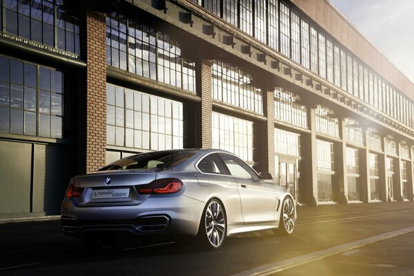 A grey BMW car is parked near the production building