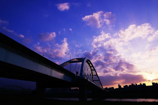 Bridge in the city across the river at sunset
