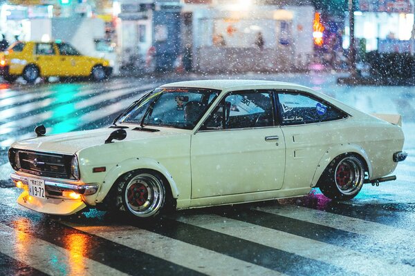 Datsun blanc sous la pluie dans la rue