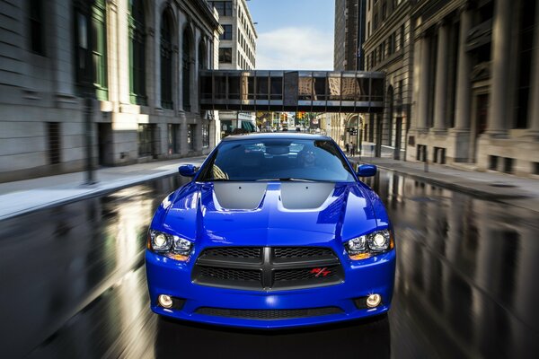 Coche deportivo azul en la carretera mojada en la ciudad