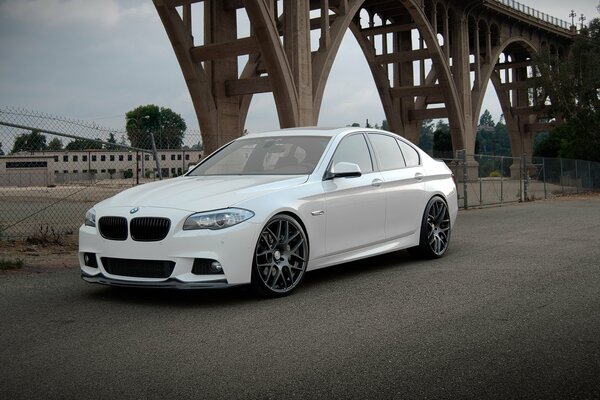 Elegante blanco BMW 550 ai bajo el puente