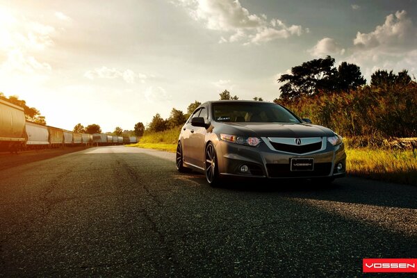 Coche acura tsx fuera de la ciudad. En el fondo va el tren de carga