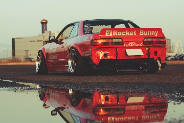 Nissan GTR rojo con reflejo en un charco