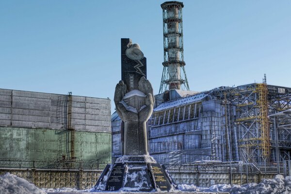 Denkmal vor dem Hintergrund eines Sarkophags über dem Kernkraftwerk Tschernobyl in einer Gefahrenzone