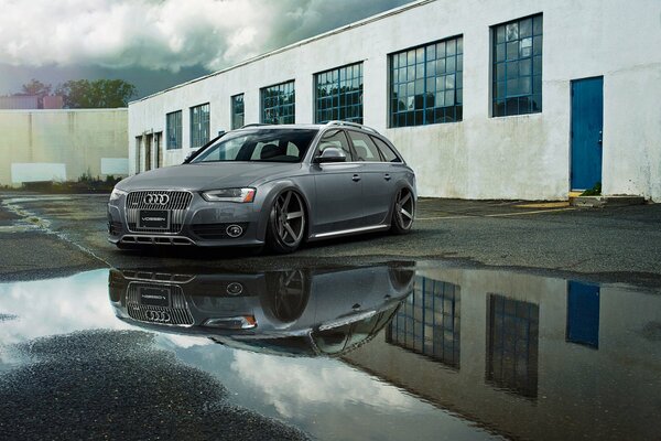 Audi a6 is standing near a puddle near the building