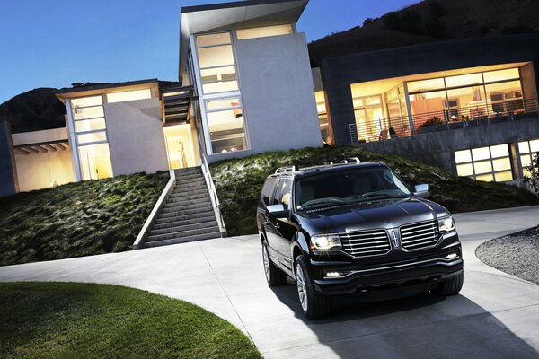 A black SUV stands in front of a large glass house