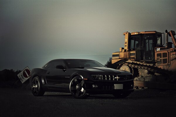 Chevrolet at dusk stands against the background of a yellow bulldozer