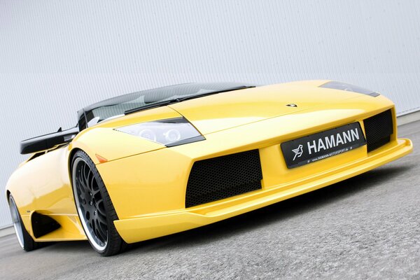 Fajny żółty supersamochód Lamborghini pod kątem na tle białej ściany