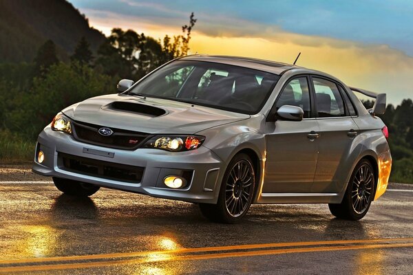 Subaru Impreza gris en el tráfico en la pista mojada