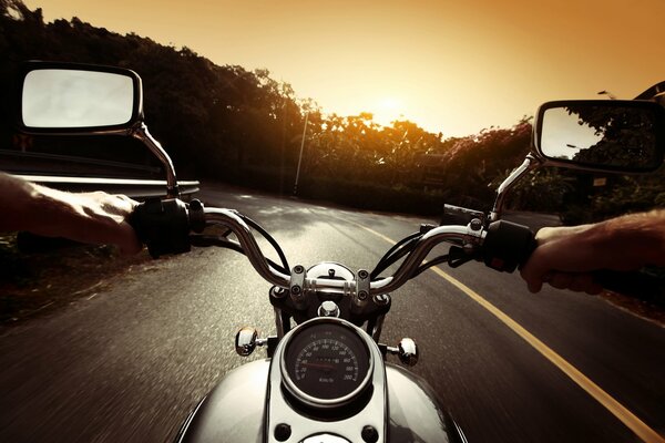 Motorradfahrer fährt auf der Straße in den Sonnenuntergang