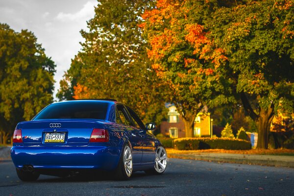 Blue audi car rides on the road with beautiful houses