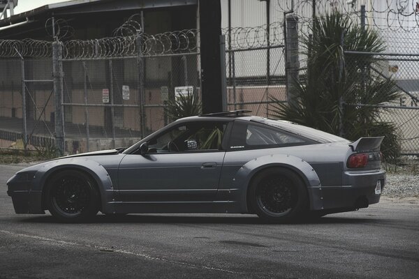 Silver Nissan car on the background of the fence