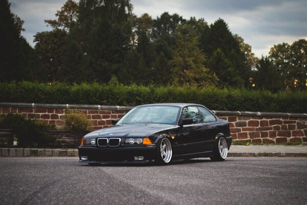 Black BMW on a background of green trees