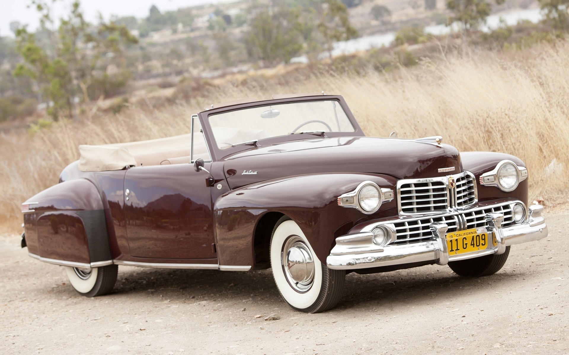 lincoln continental cabrio 1947 lincoln.continental weinrot front retro straße.gras hintergrund