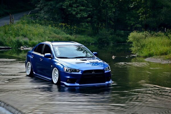 Il marchio automatico blu Mitsubishi Lancer cavalca sull acqua