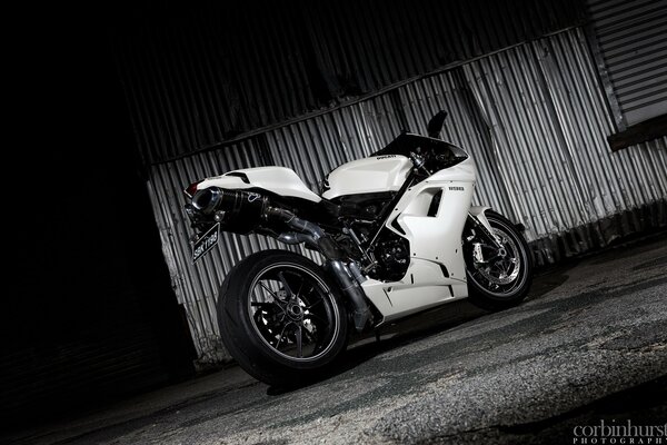 Black and white photo of a motorcycle near an iron wall