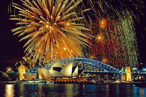 Fuegos artificiales sobre el puente y su reflejo en el río