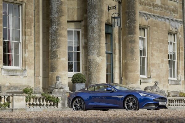 A blue car near a house with columns